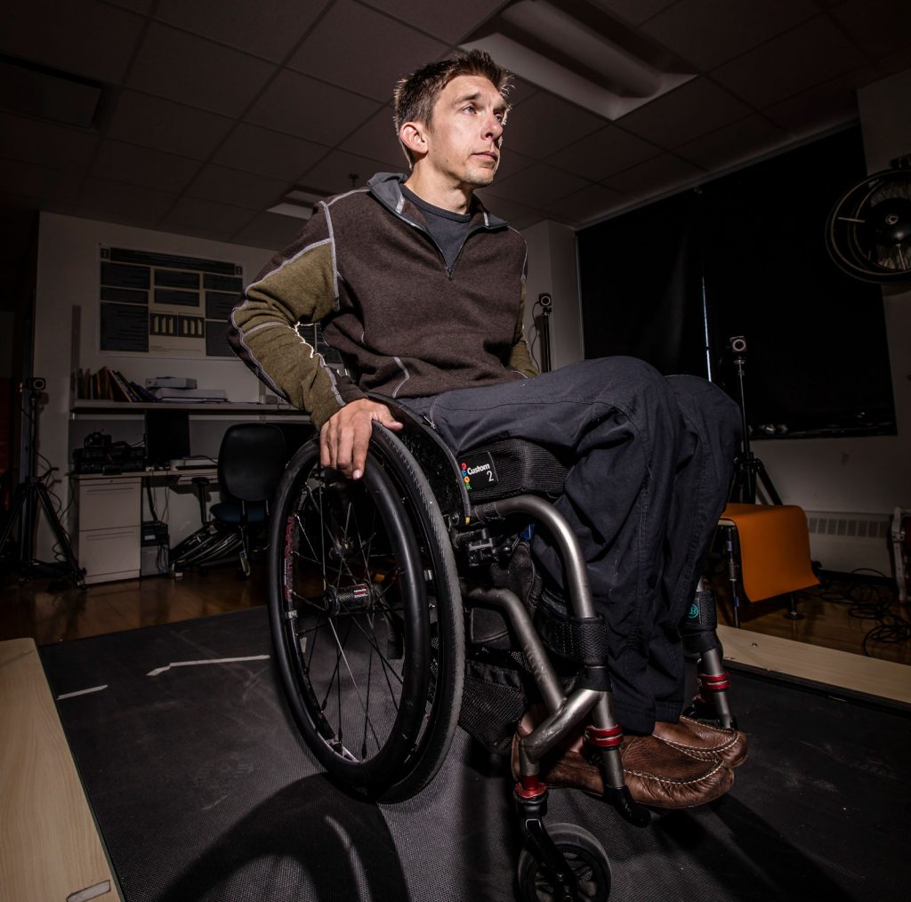 A man in a wheelchair as he is getting ready to move while a light in the center of the room shines on him
